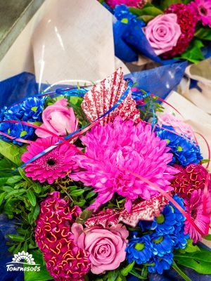 Bouquet coloré avec chrysanthèmes roses, roses, gerbera, fleurs bleues et feuillage, étiquette Tournesols.